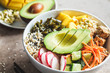 Vegan poke bowl with avocado, tofu, rice, seaweed, carrots and mango. Vegan food concept.