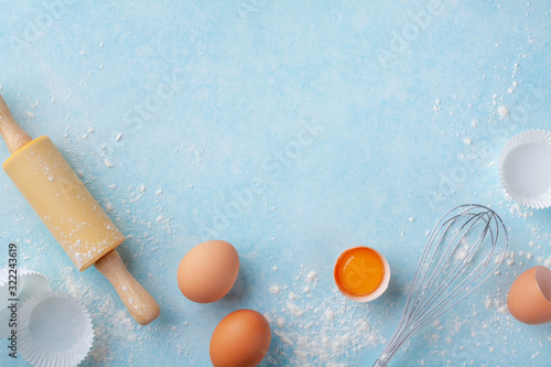 Fotografía Baking background with rolling pin, whisk, eggs, flour on blue table top view