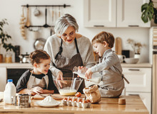 Happy Family Grandmother And Grandchildren Cook In The Kitchen, Knead Dough, Bake Cookies.