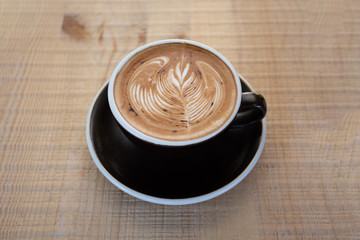 A flat lay black cup of coffee placed on a wooden table by the window in shop,