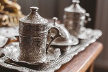 Closeup Shot Of An Antique Silver Tea Set With A Blurry Background