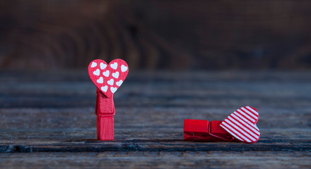 Wall Mural - Two little red clothespins hearts. On a wooden background. Love