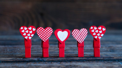 Wall Mural - A lot of little red clothespins of hearts. On wooden background