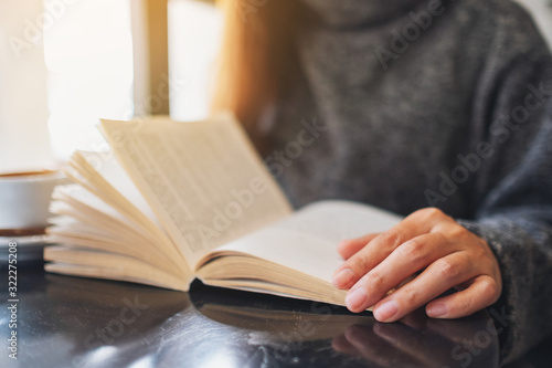 Fotomural Closeup image of a woman opening and reading a vintage novel book on the table