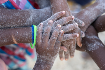 many african children hands connecting on sand beach, tanzania, africa
