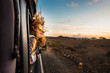 Leinwandbild Motiv beautiful caucasian young woman travel outside the car with wind in the curly hair, motion and movement on the road discovering new places during a nice sunset, enjoy and joyful freedom concept