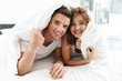 © Drobot Dean - Attractive happy young couple laying on bed in the bedroom