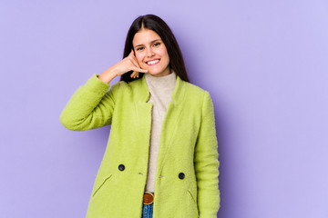 Young caucasian woman isolated on purple background showing a mobile phone call gesture with fingers.