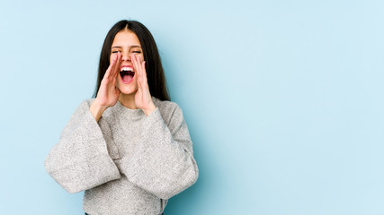 Young caucasian woman isolated on blue background shouting excited to front.