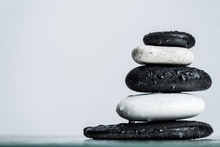 Close Up View Of Water Drops On Stacked Black And White Zen Stones On Wet Glass Isolated On Grey
