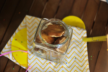 Shell shaped cookies in a glass jar on a background of a composition of paper figures on a wooden table