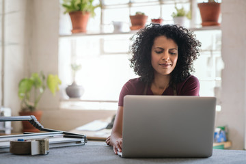 Young woman working on a laptop in her framing shop