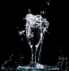 Wall Mural - Water with splashes in a glass on a black background