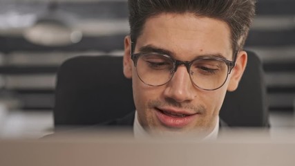 Poster - Close up view of Happy businessman in formal suit and eyeglasses using laptop computer while sitting in office