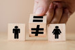 © Dilok - Hand flipping wooden equal and unequal cubics between man and woman.Gender equality concept.