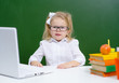 © Ermolaeva Olga - Cute little girl in glasses is typing in concentration on a laptop in class at school, an apple lies with her