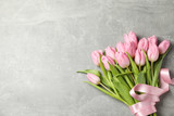 Fototapeta Tulipany - Tulips with ribbon on grey background, top view