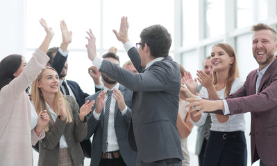 group of cheerful company employees congratulating their colleague