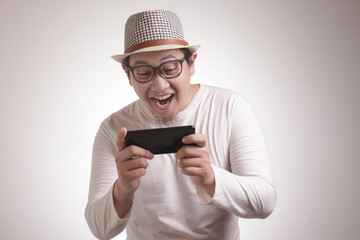 Funny Young Asian Guy Playing Games on Tablet Smart Phone