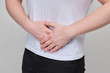 © gesrey - A man in a white T-shirt massages his stomach due to severe pain in the pancreas, intestine.