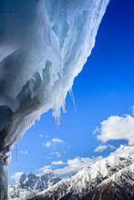 Hanging Icicle With Blue Sky And High Mountains In The Background