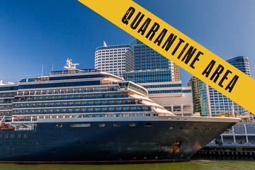 Yellow quarantine sign over a cruise ship docked at port