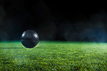 Wall Mural - Black Football on an illuminated empty sports field at night.