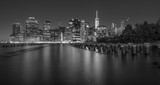 Fototapeta Miasto - Dramatic, black and white New York City skyline from Brooklyn Bridge Park at night.