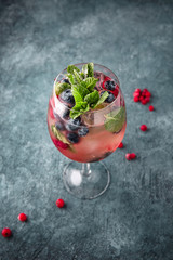 Wall Mural - Refreshing low-alcohol cocktail with champagne, liquor, mint, berries and syrup. On a turquoise background. Cocktail menu. Sea mood concept.