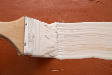 brush with white paint on brown surface