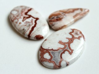 Crazy Lace Agate mineral (banded chalcedony, microcrystalline quartz) with red and brown frilly pattern, mined in Mexico. Oval shaped polished cabochon is ready for setting in jewellery.