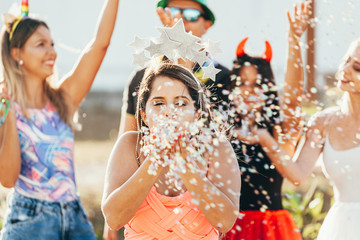 Wall Mural - Brazilian Carnival. Young woman in costume enjoying the carnival party blowing confetti