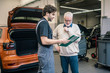 © Westend61 - Car mechanic explaining check list to client in workshop