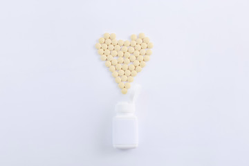 Wall Mural - Pharmaceutical medicine pills spilling out of pill bottle in shape of heart on white background, top view