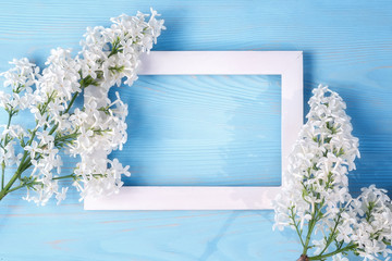 Wall Mural - Spring or summer floral background for greeting card. White lilac and wooden frame on a blue background. Template for design with copy space.