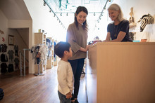 Shop Assistant Serving Mother With Son In Clothing Boutique