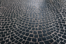The Paving Stones Laid Laid Out In A Semicircle. The Texture Of The Old Dark Stone. Road Surface. Vintage, Grunge.