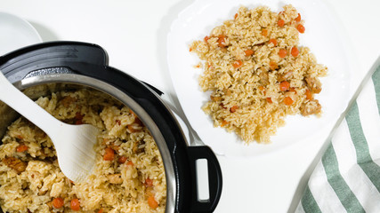 Wall Mural - Rice, vegetables, and meat in a pot and on a plate. Cooking rice with meat and vegetables (or Rice Pilaf)  in pressure multi cooker step by step, top view.