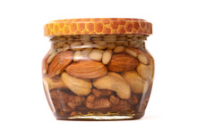 Mix Of Honey With Nuts - Cashews, Almonds, Walnuts And Pine Nuts In A Glass Small Jar On A White Background. The Concept Of Healthy Eating And Healthy Foods.