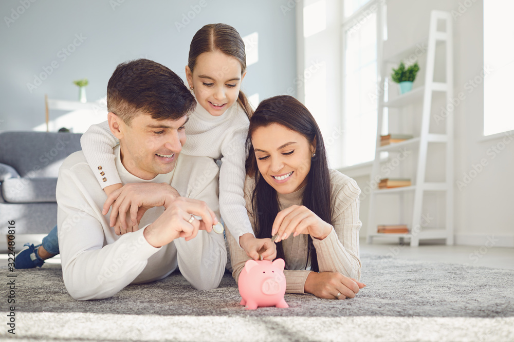Happy family saves money in a piggy bank pig. Stock Photo | Adobe Stock
