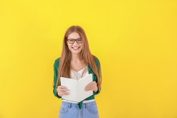 Poster - Beautiful young woman with book on color background