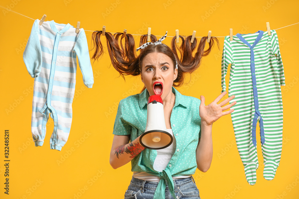 Funny housewife with laundry and megaphone on color background