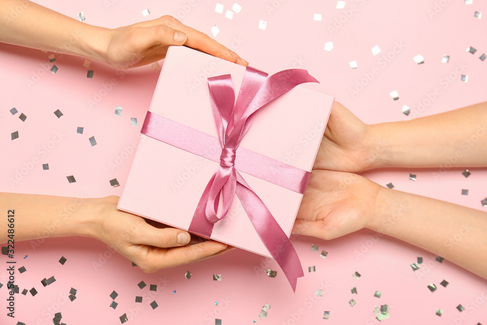 Female hands with beautiful gift box on color background