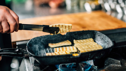 Wall Mural - Chef's Hand Frying Sliced Tofu Cheese in Vegan Restaurant