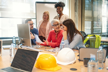 Group of creative designers brainstorming and working on a project. Young modern designer people with leader senior woman at meeting. Business people working and discussing together in meeting