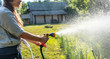 Hipster young woman watering plants a country house, summer and garden care, organic products, eco-friendly lifestyle