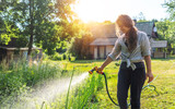 Hipster young woman watering plants a country house, summer and garden care, organic products, eco-friendly lifestyle