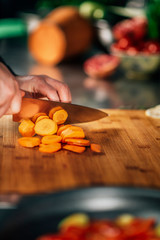 Wall Mural - Preparing Vegan Meal -  Chef Cutting Carrot on Wooden Cutting Board