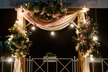 Night Wedding Ceremony With Arch, Flowers, Cloth And Bulb Lights On The Backyard Outdoors, Copy Space. Wedding Decor