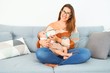 © Krakenimages.com - Young beautiful woman and her baby on the sofa at home. Newborn and mother relaxing and resting comfortable drinking milk using feeding bottle